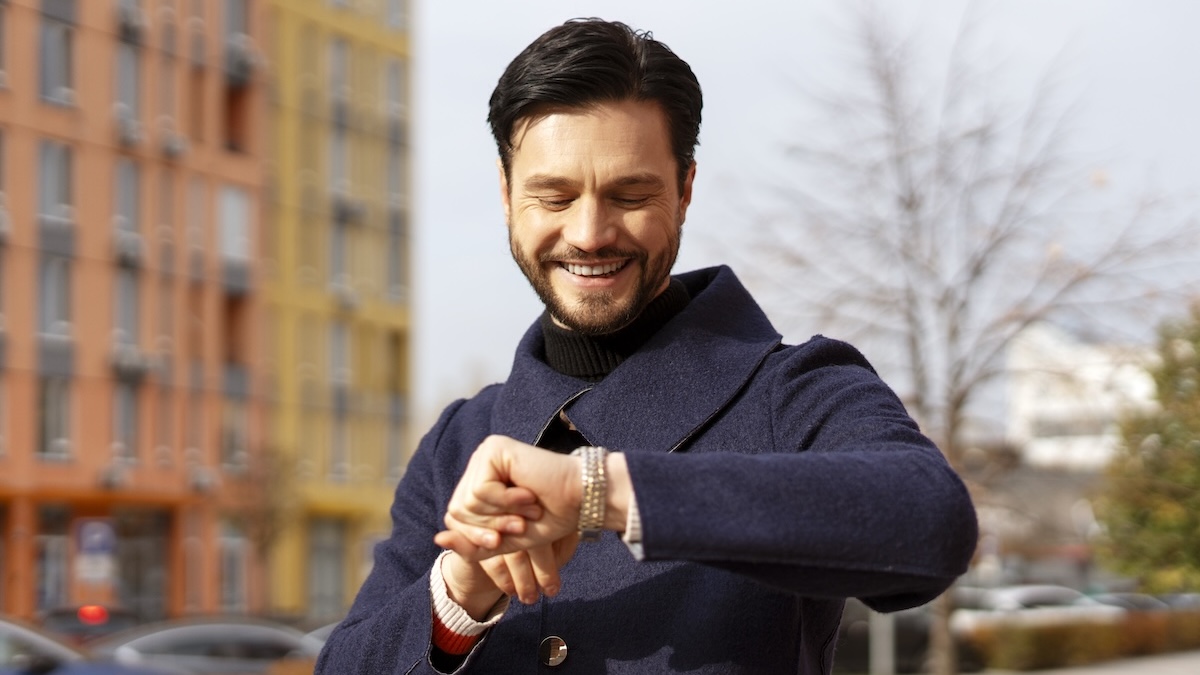 Mann im Herbst checkt Uhrzeit