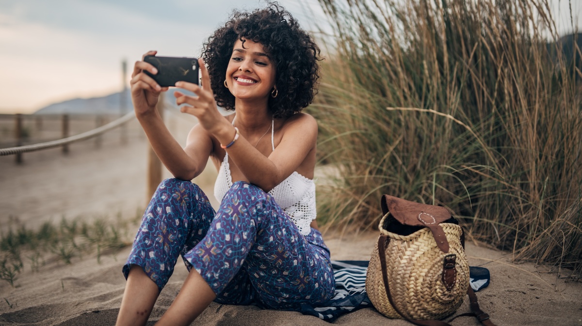 Laughing woman takes photos with cell phone on vacation